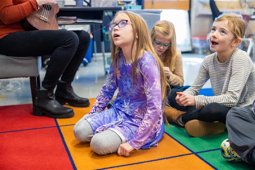 A teacher plays a ukulele for her students
